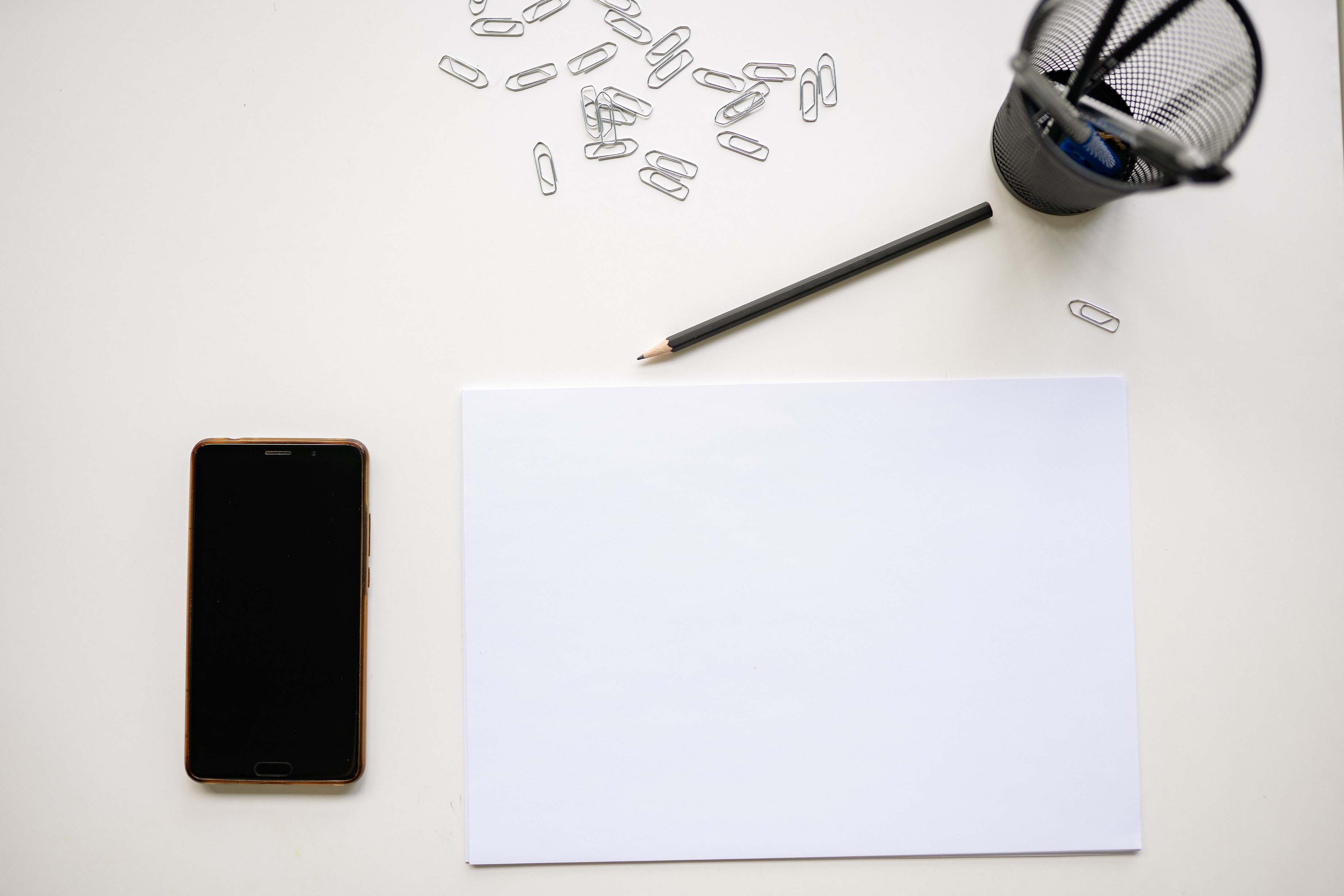 Schreibtisch mit Belegen und Unterlagen, Smartphone und Stift auf Papier